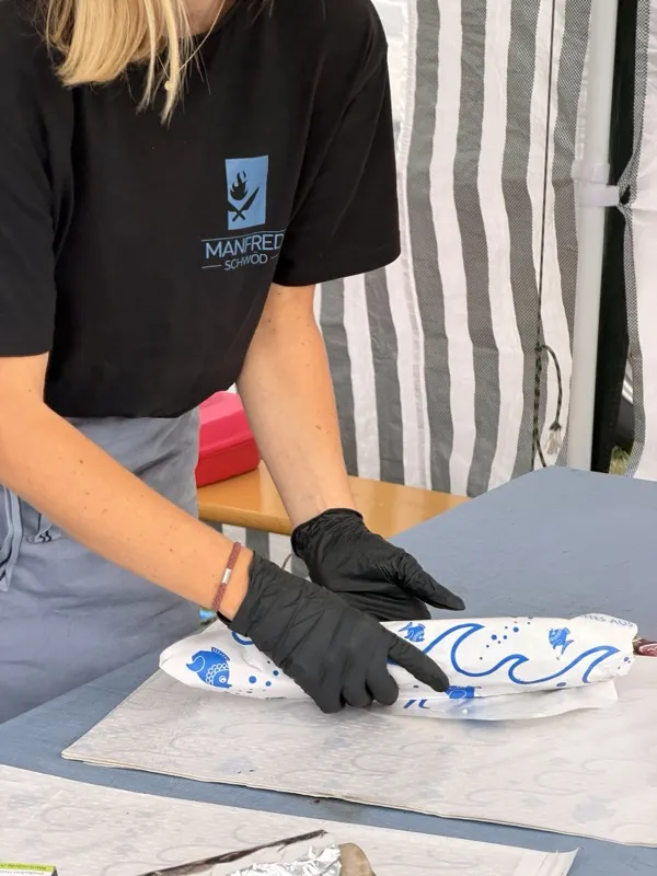 Fertiger Fisch wird in blau bedrucktes Fischpapier eingeschlagen