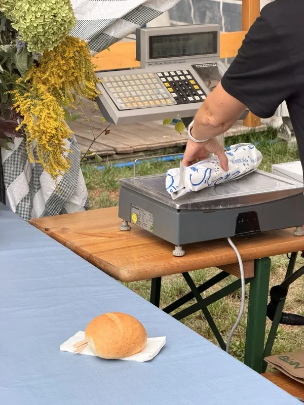 Eingepackter Steckerlfisch auf der Waage, daneben eine Semmel