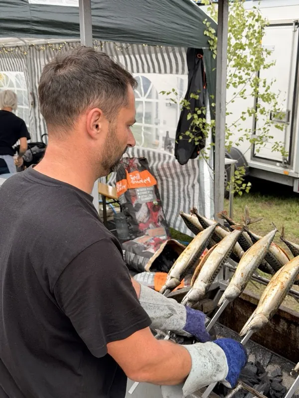 Griller steckt frische Makrelen auf die Metallsteckerl